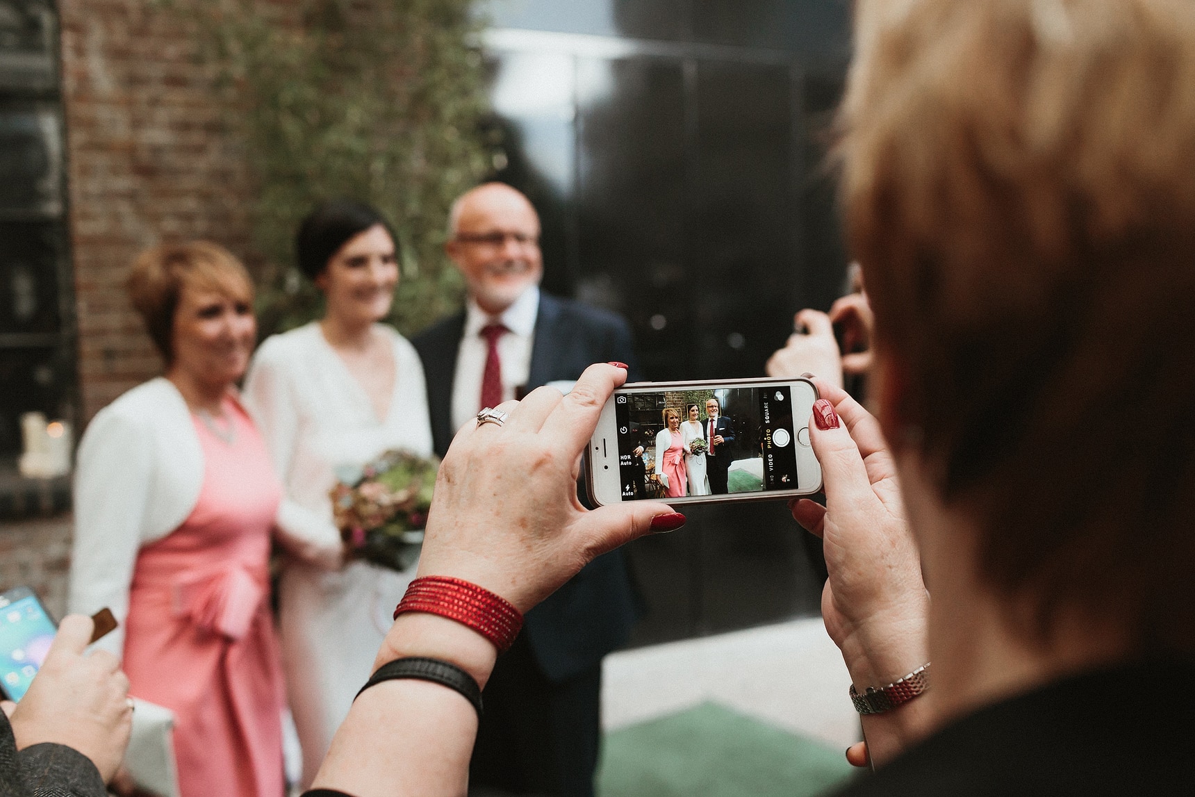 wedding guest taking photo of bride and her parents