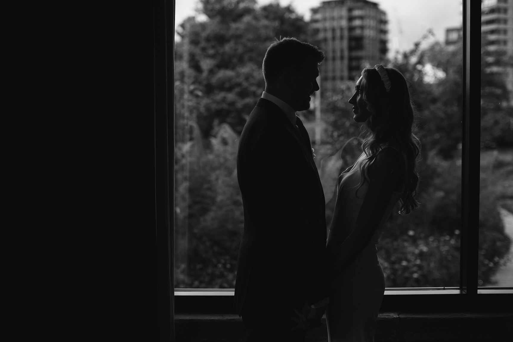 Black and white wedding portrait silhouette in front of a window with London skyline in the background