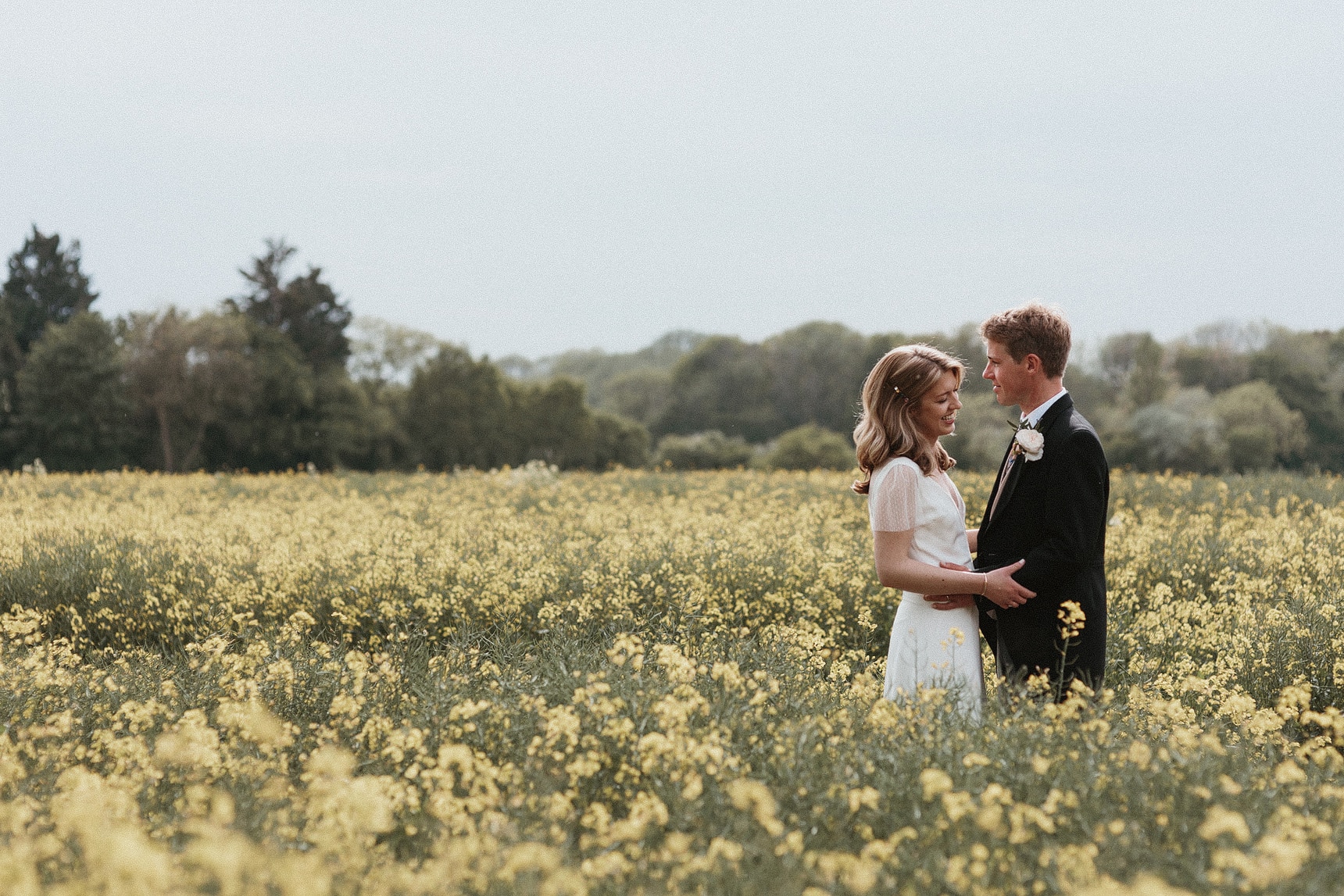 Bride and groom having their portraits taking in a yellow flower field