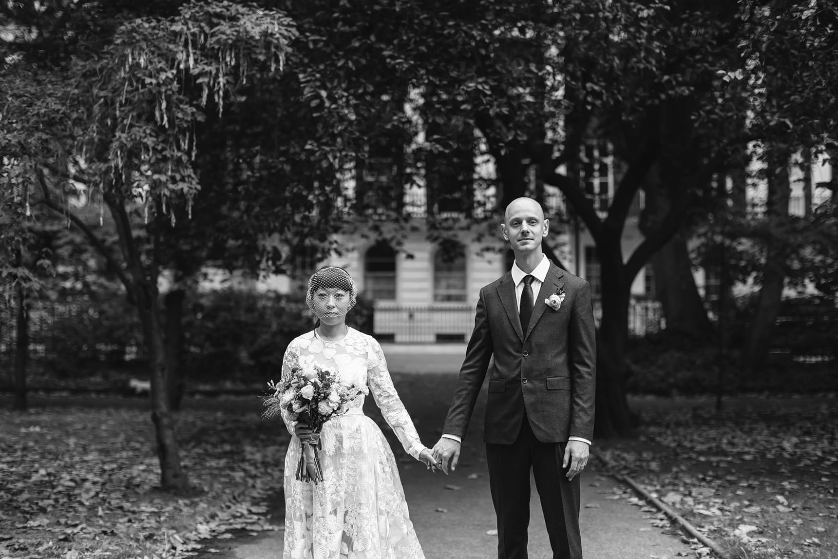 Black-and-white photograph with bride and groom holding hands