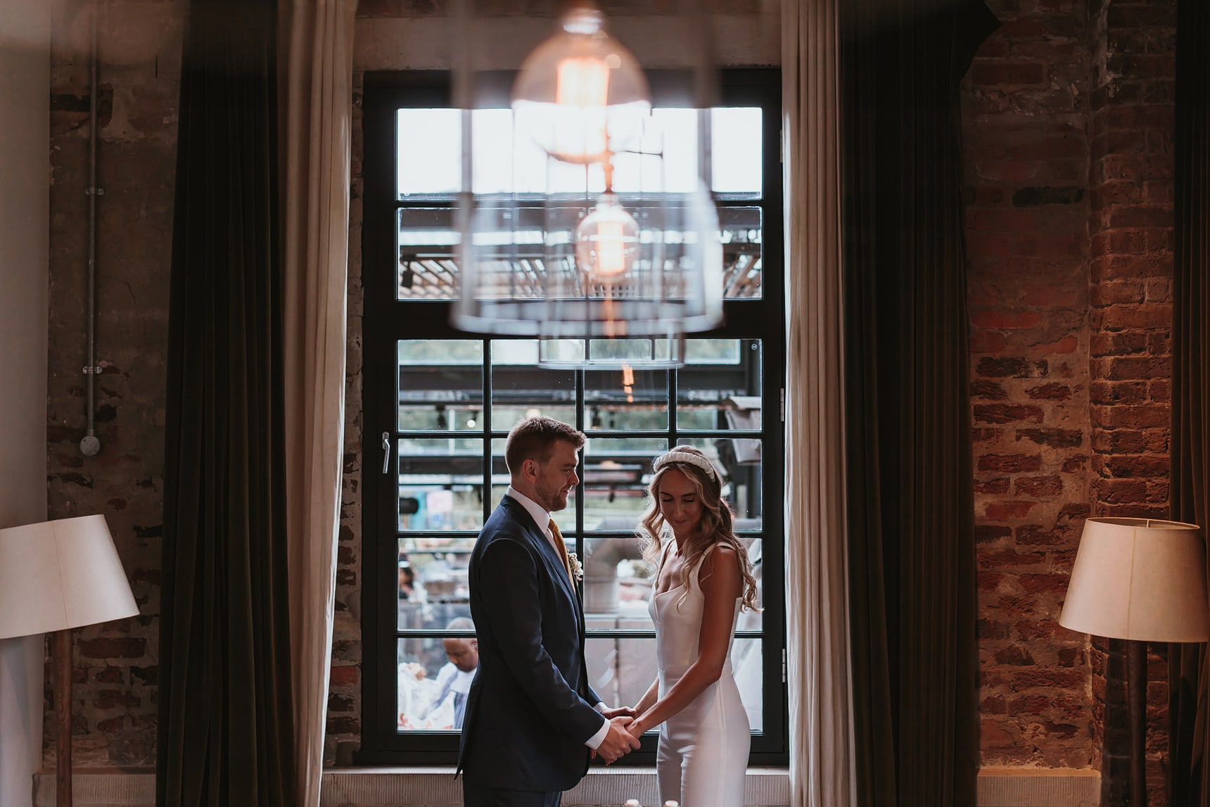 Bride and groom stand in front of the window with symmetry in the photo